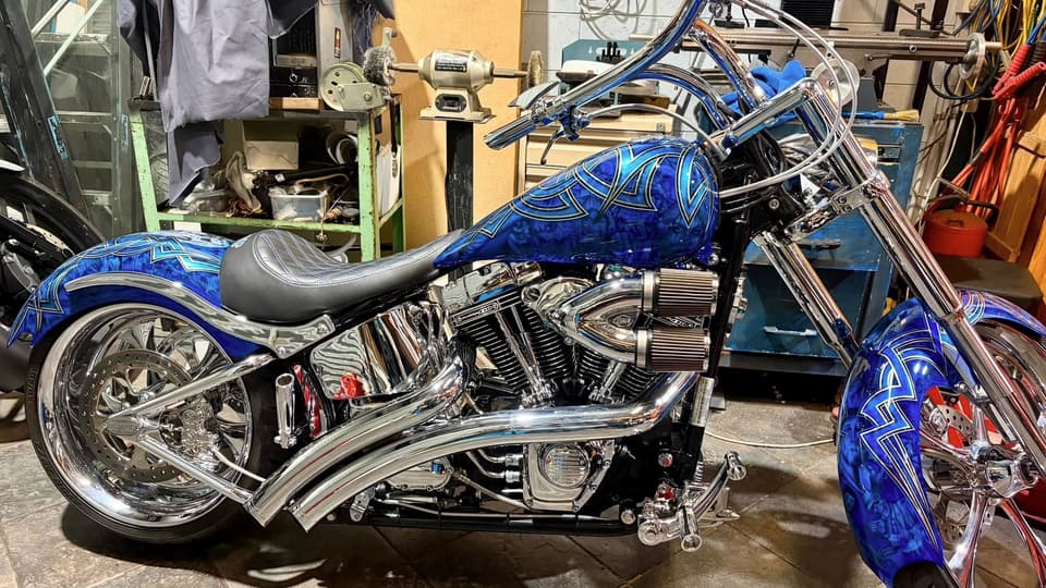 Chrome and candy-blue custom Softail with pinstriped tank, in the workshop