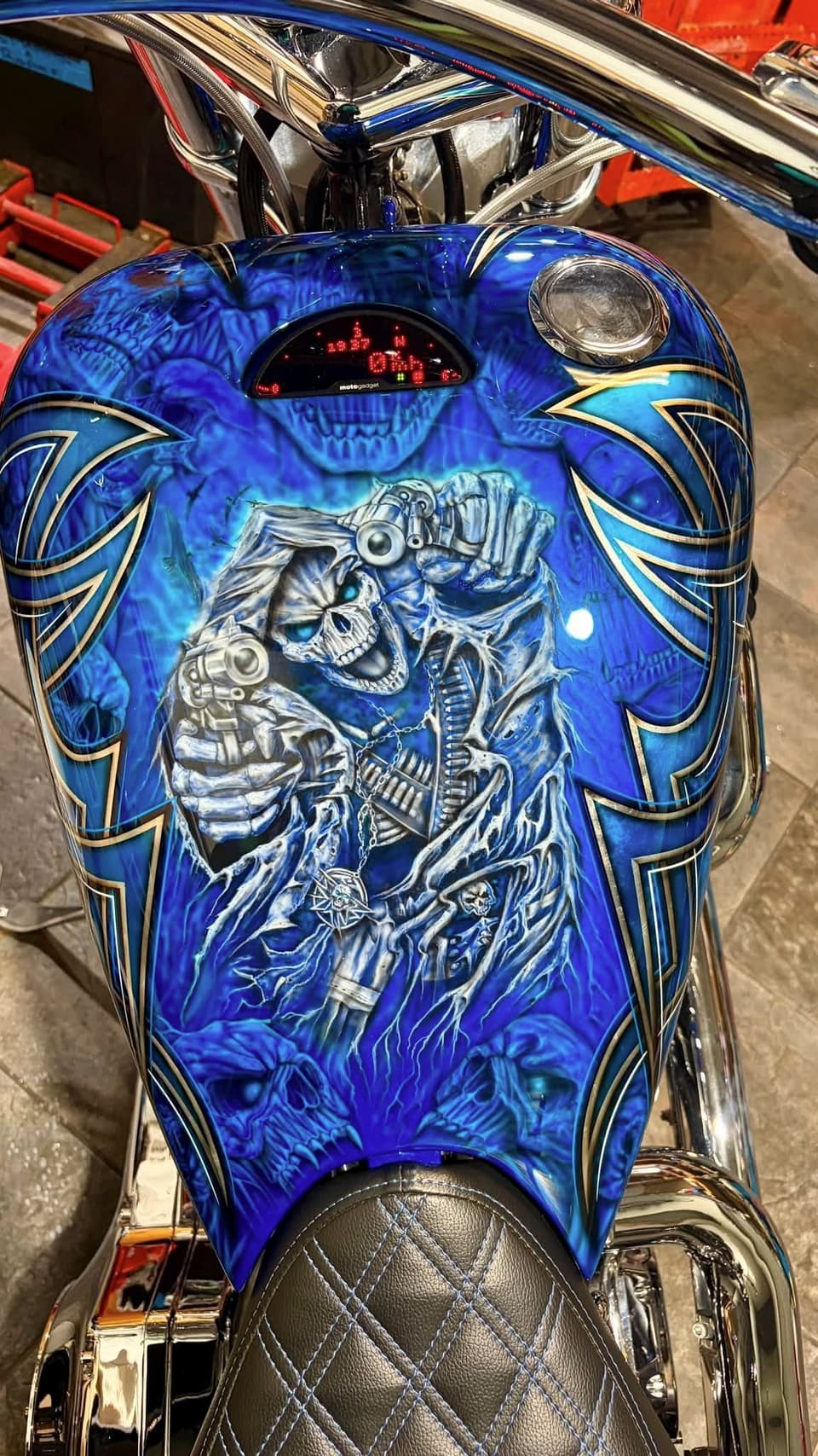 Airbrushed skull artwork and pinstriping on a blue fuel tank